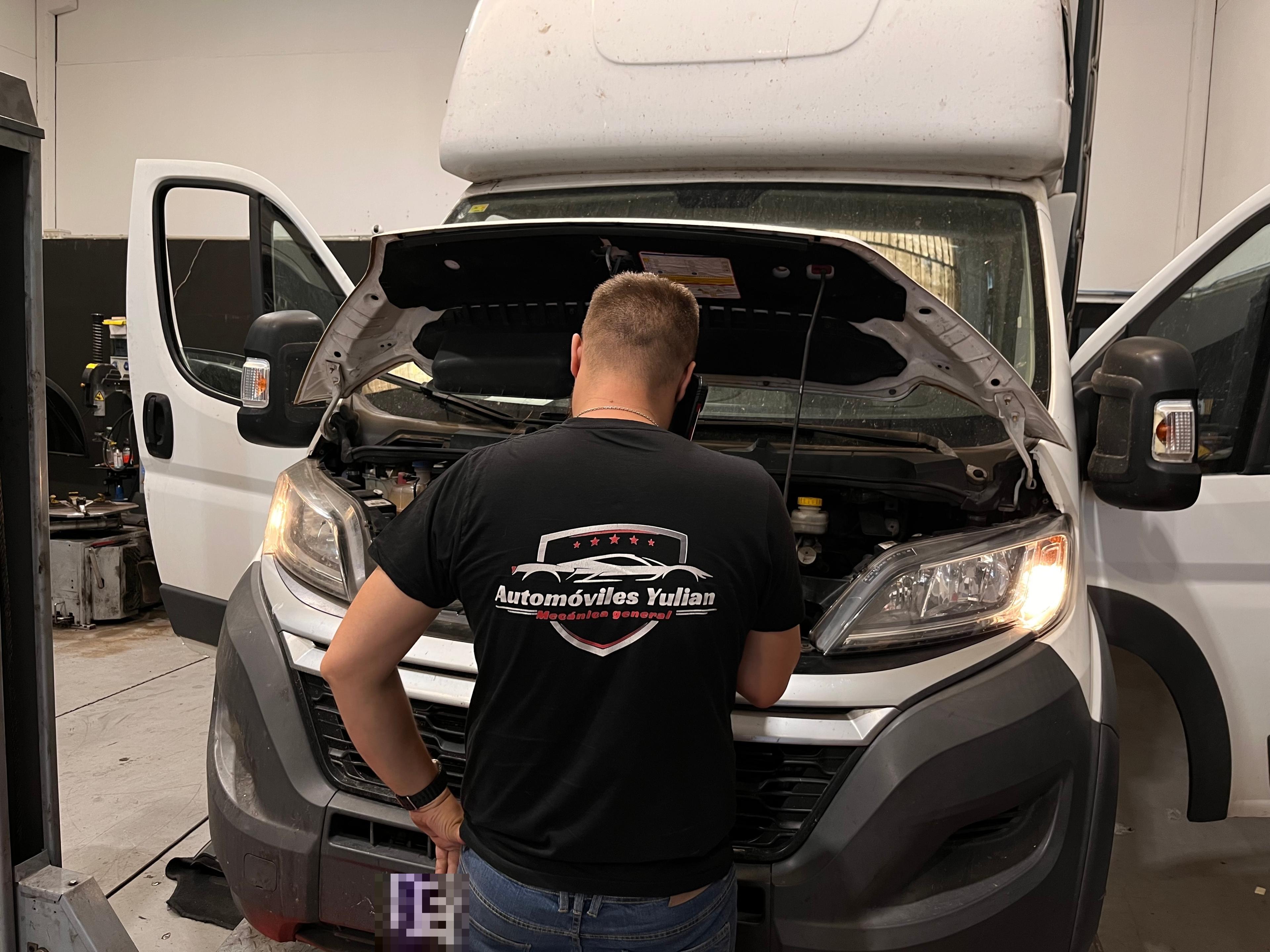 Técnico de Automóviles Yulian revisando una furgoneta comercial en el taller