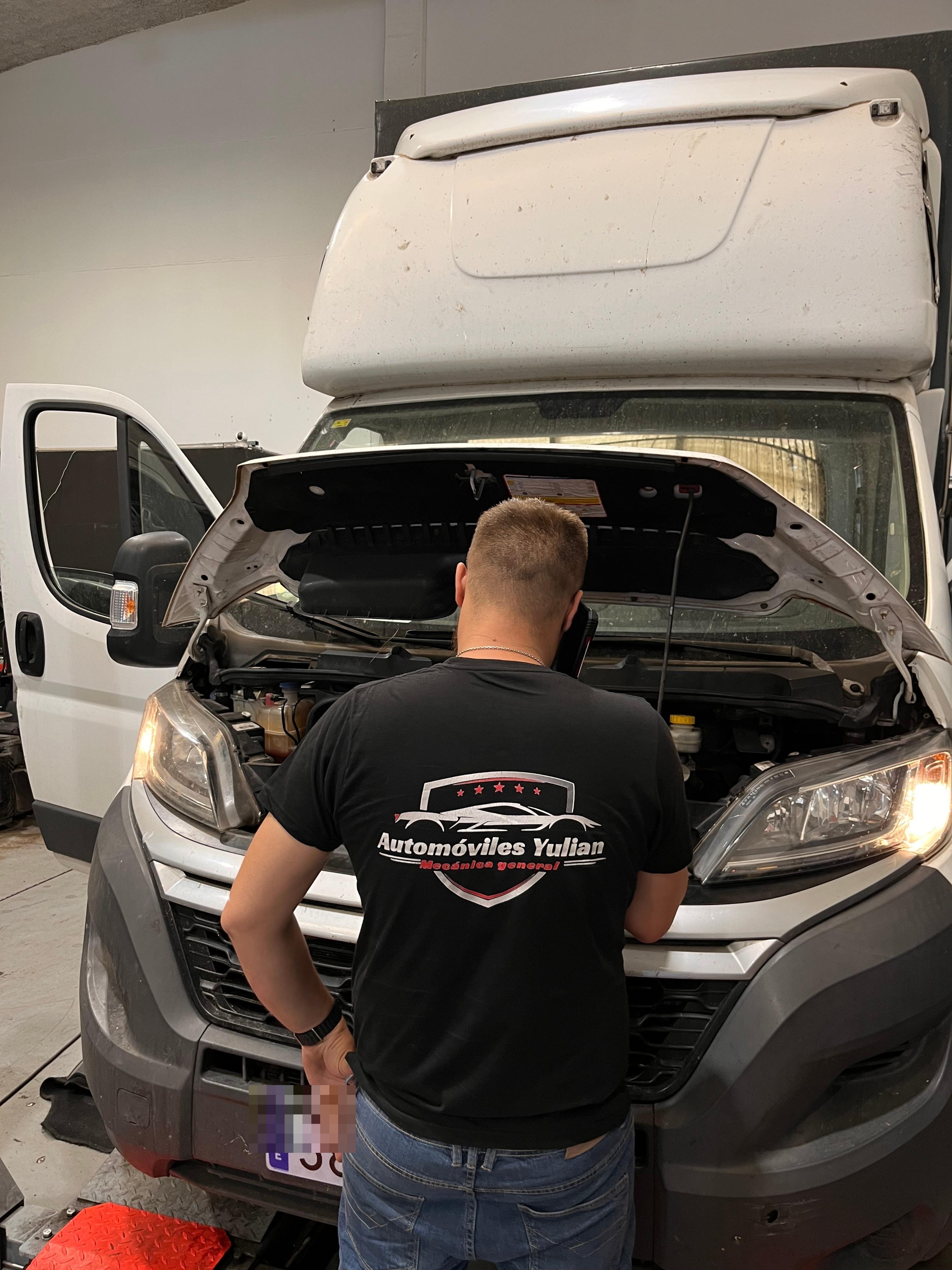 Técnico de Automóviles Yulian junto a una furgoneta en el taller